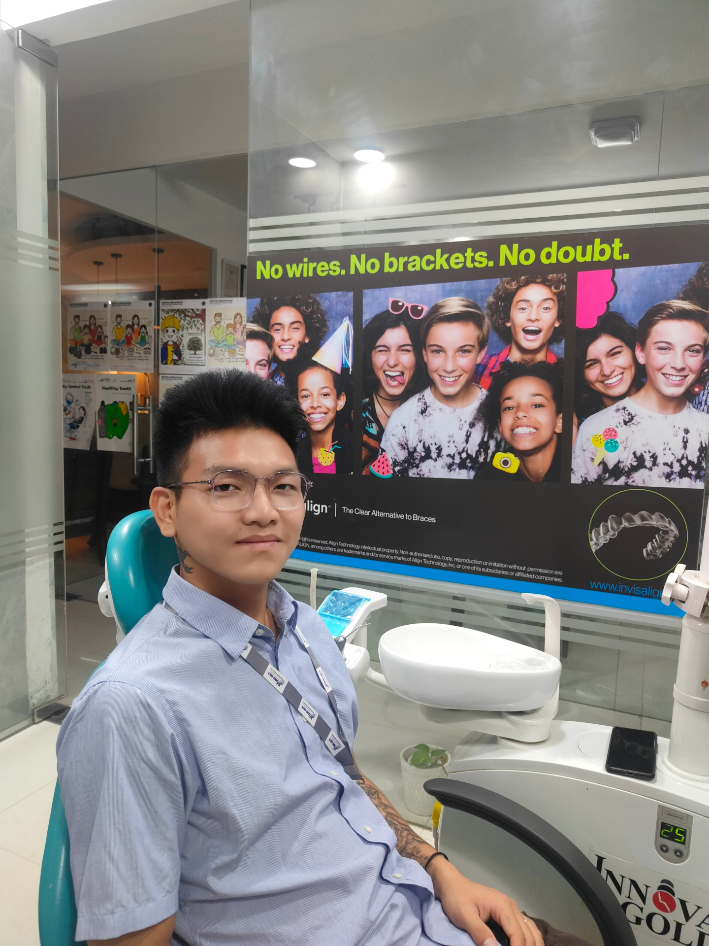 A patient seated at Dental Brasstacks Gurgaon beside the Invisalign clear-aligner display